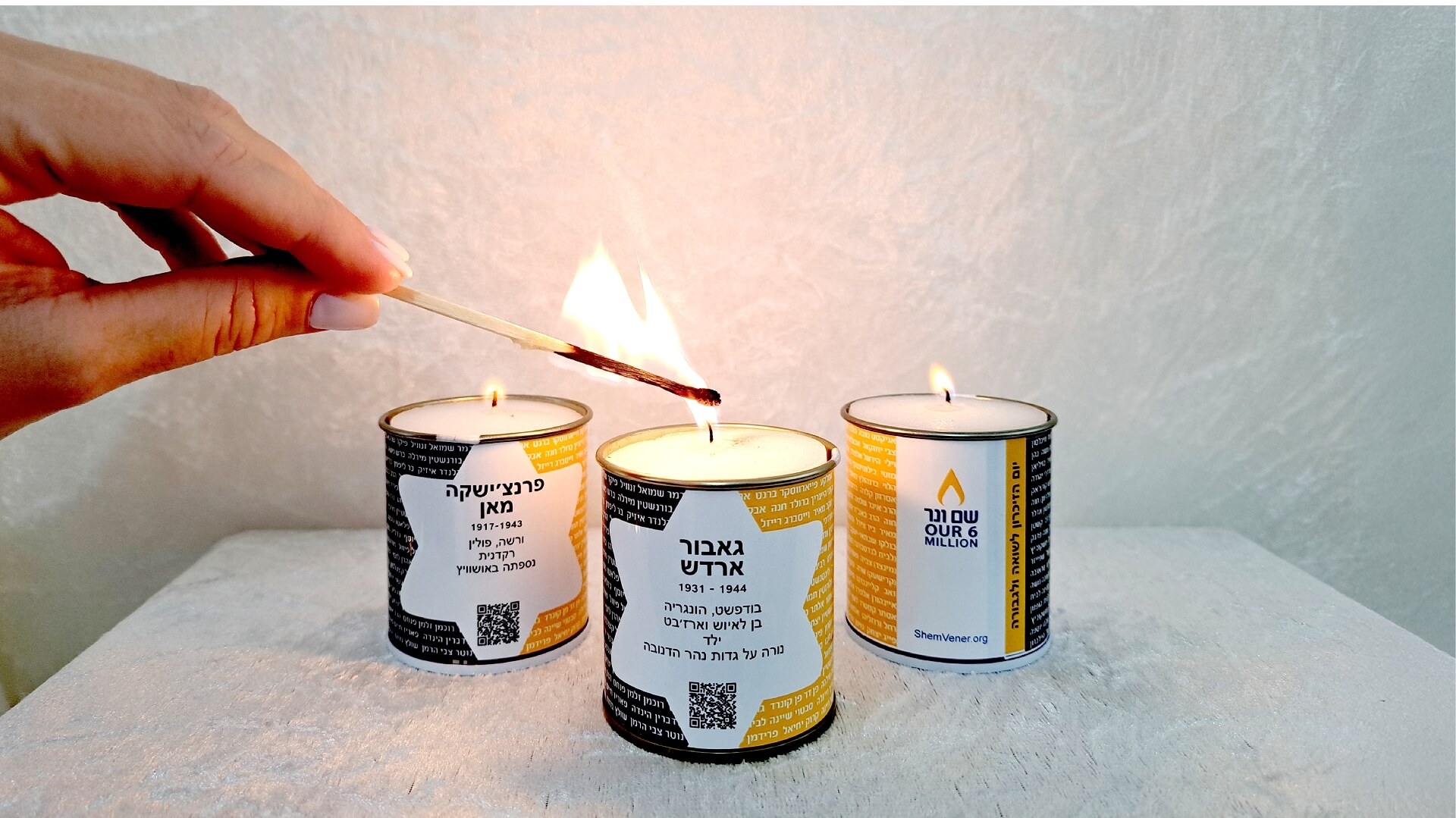 יד מחזיקה גפרור ומדליקה 3 נרות נשמה